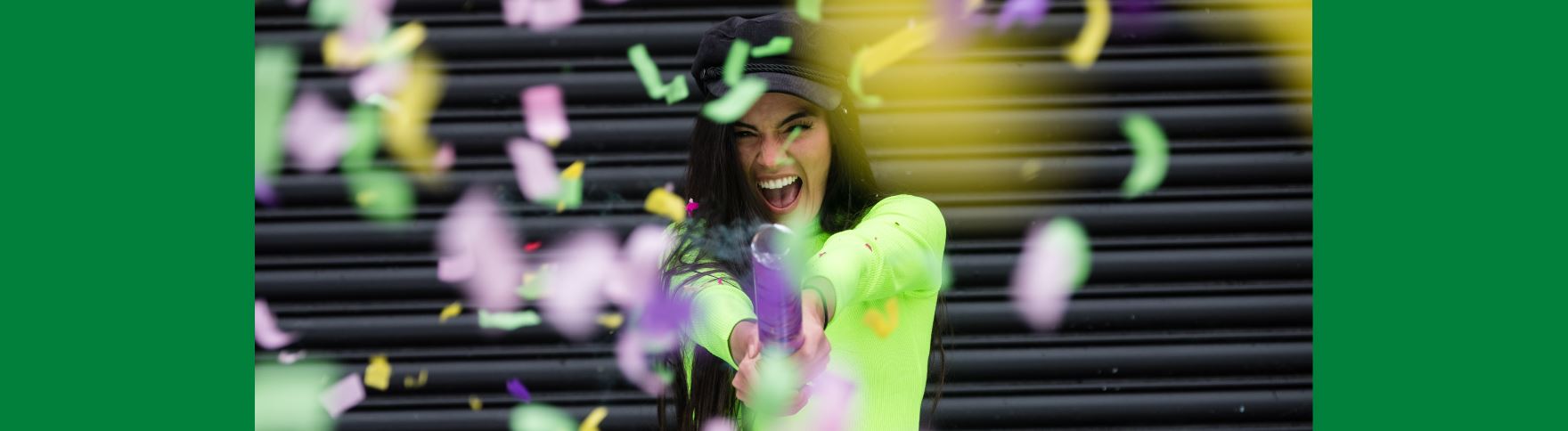 A girl holding a party-popper towards the camera, with confetti streaming down