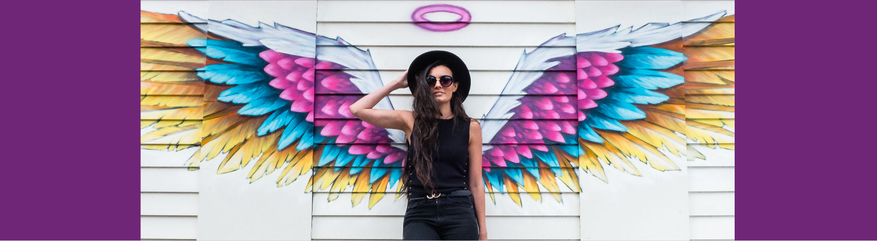 A woman standing in front of a pair of graffiti angel wings
